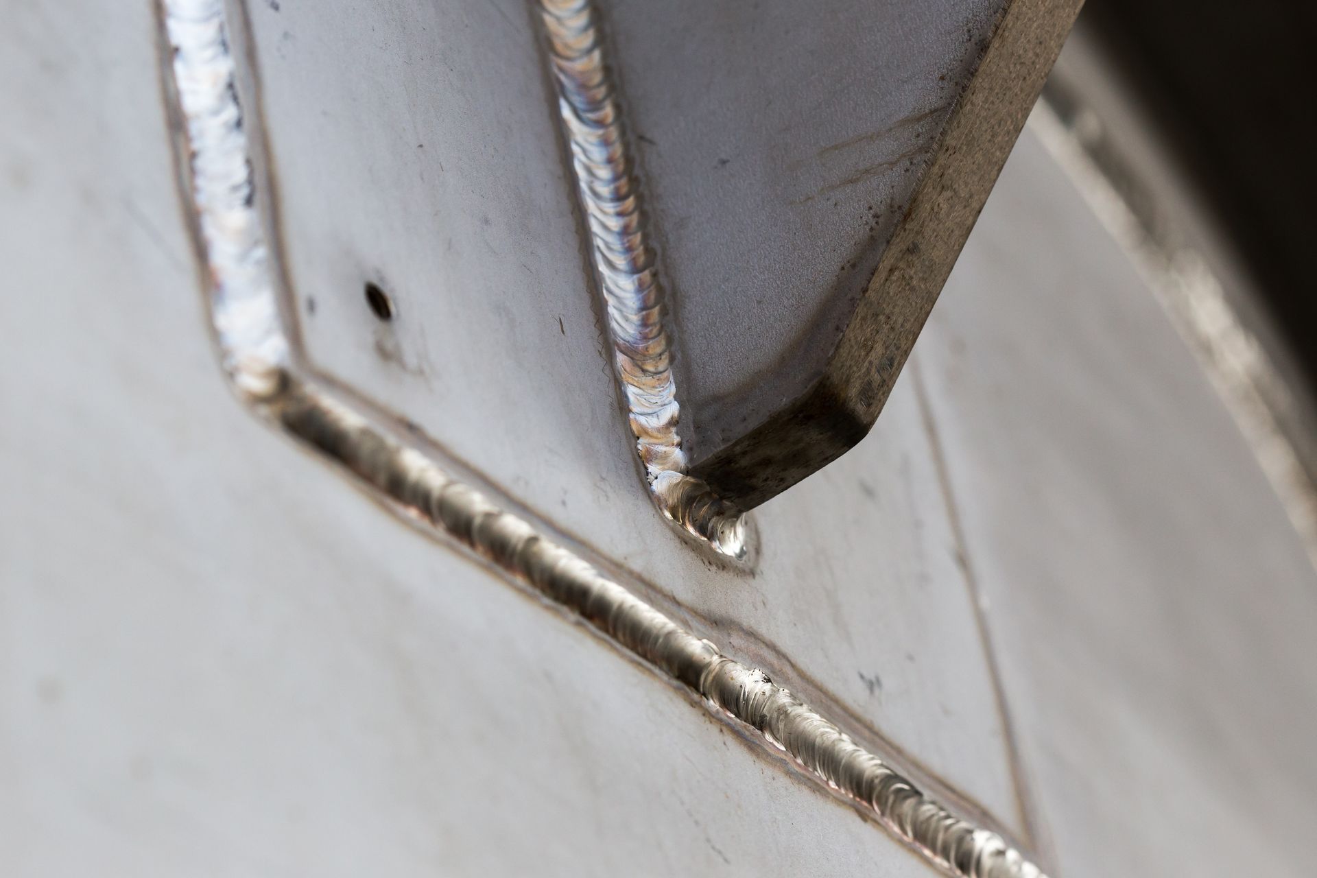 Close-up of a welded metal joint on a gray industrial surface