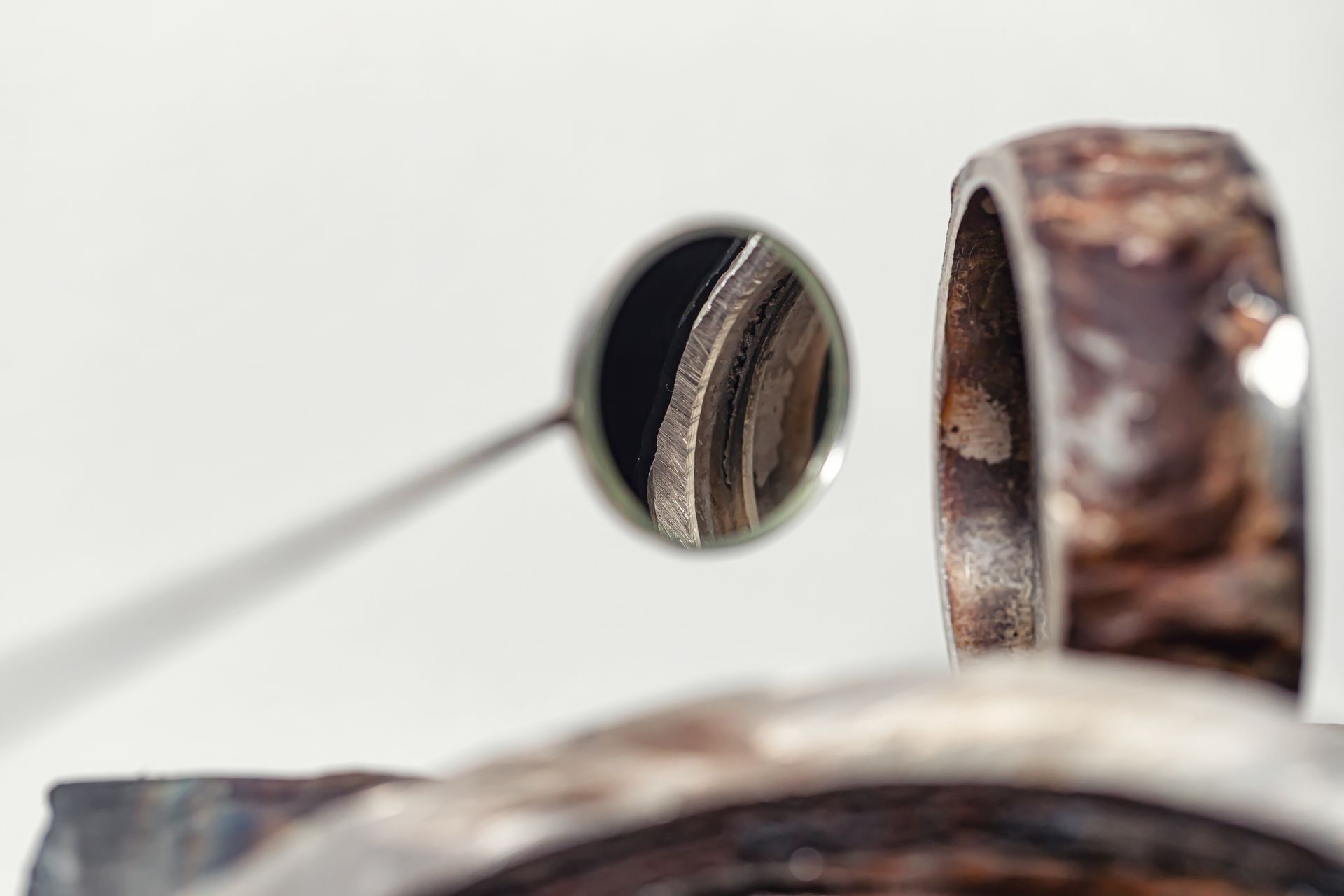 Close-up of a small round mirror and a brown speckled ring on a white background