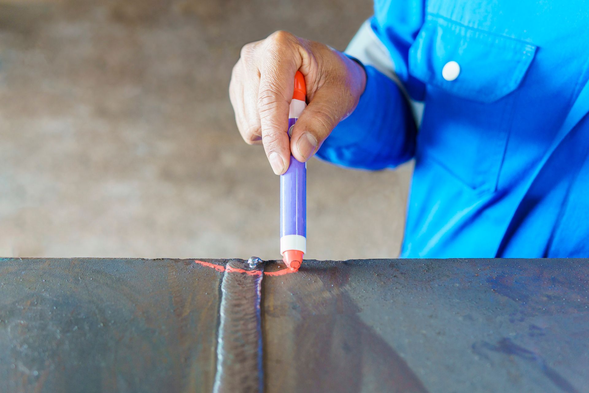 Person welding a metal seam with a handheld tool, sparks visible, in a workshop.