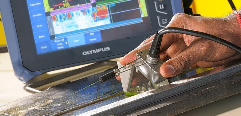 A person is using a ultrasonic device on a piece of metal. A person is using a ultrasonic device on a piece of metal.