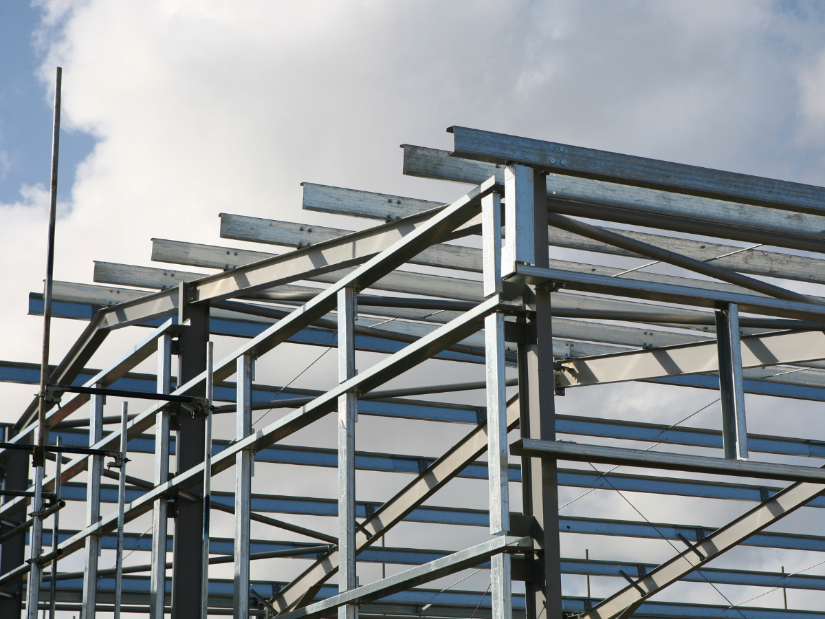 A metal structure under construction with a blue sky in the background Metal framework of a building under construction against a cloudy sky.