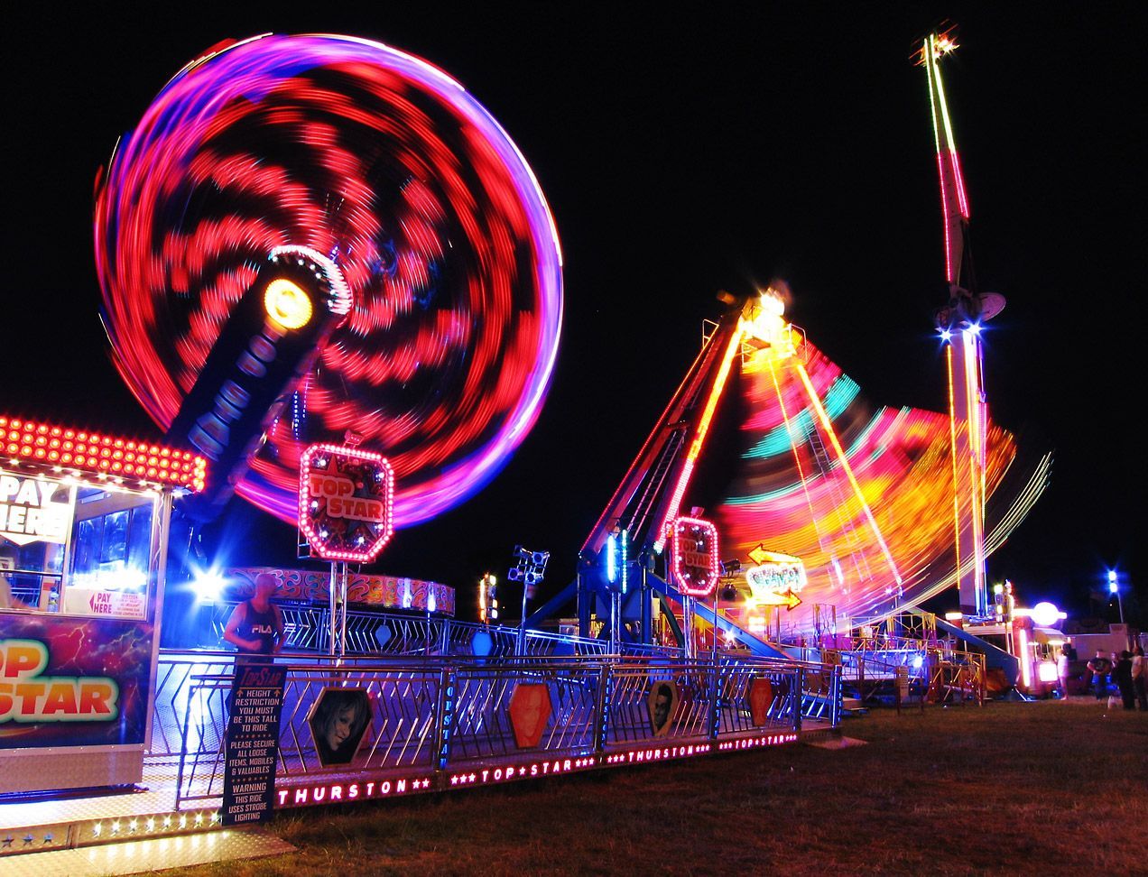 An amusement park at night with a ferris wheel that says ' swirl ' on it