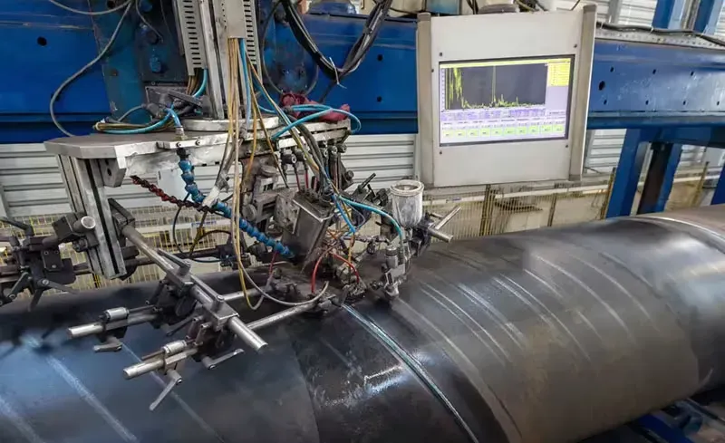 A machine is cutting a pipe in a factory.