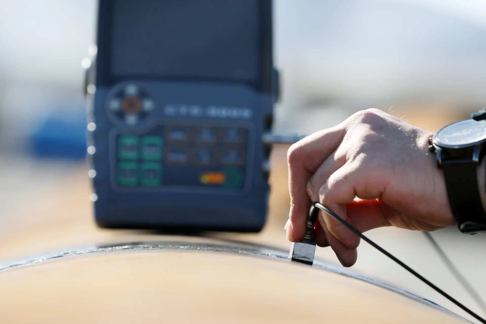 A person is using a device to measure the thickness of a piece of metal. A person is using a device to measure the thickness of a piece of metal.