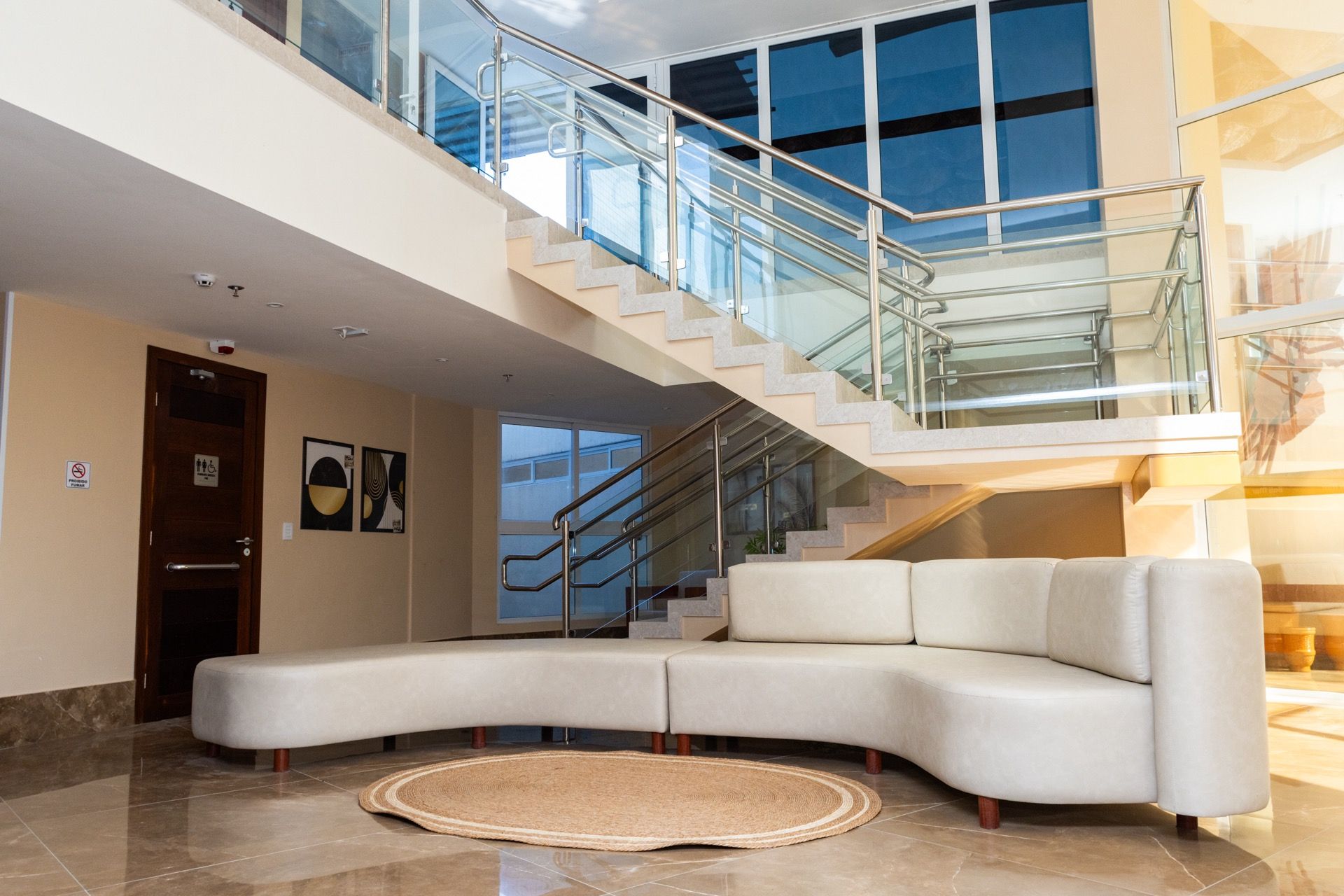 Uma sala de estar com um sofá e escadas ao fundo.