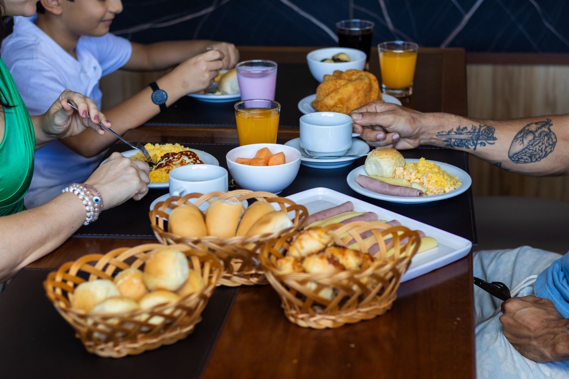 Uma família está sentada à mesa tomando café da manhã.