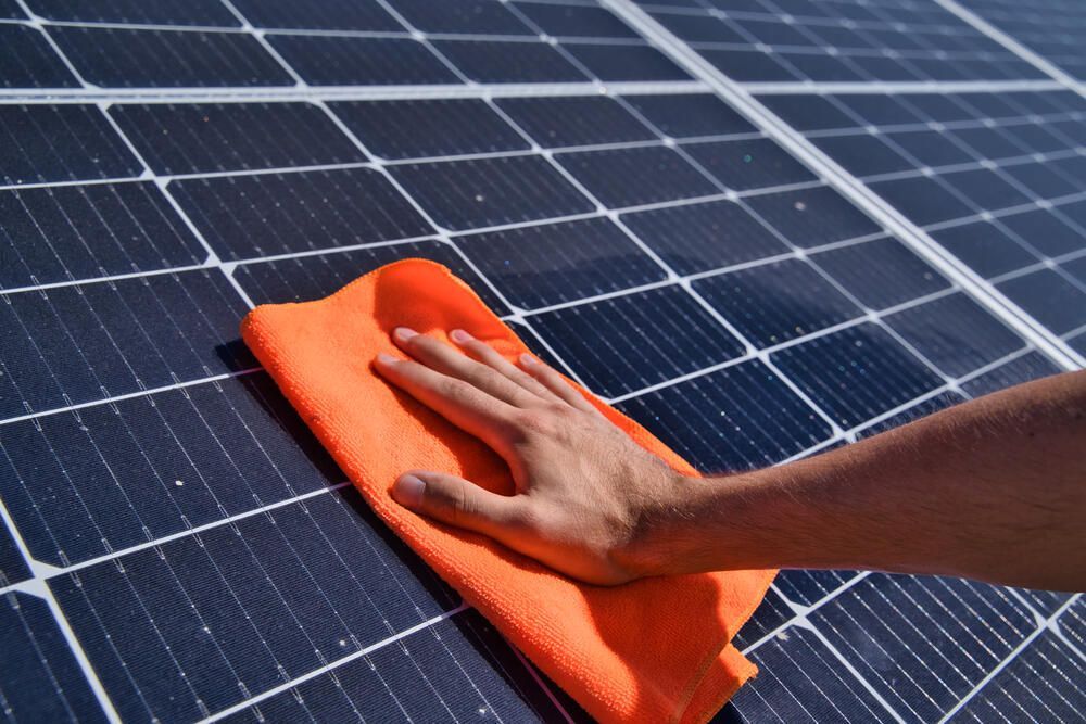 Person is Cleaning a Solar Panel With an Orange Cloth — Abstract Window Cleaning in Kingscliff, NSW