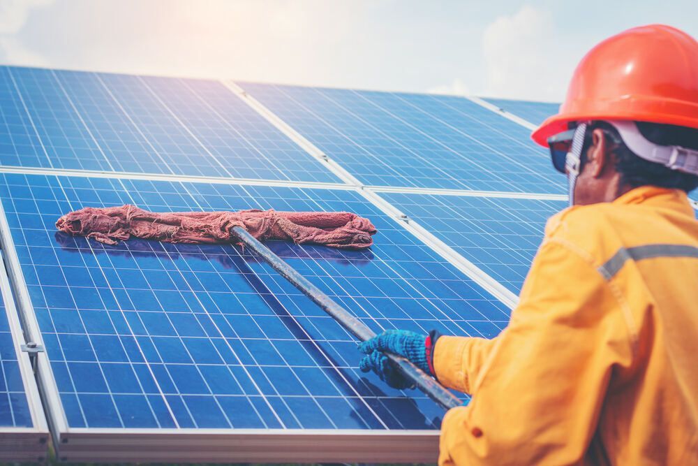 Man is Cleaning Solar Panels With a Mop — Abstract Window Cleaning in Pottsville, NSW