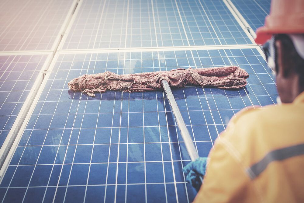 Man is Cleaning Solar Panels With a Mop — Abstract Window Cleaning in Hopkins Creek, NSW
