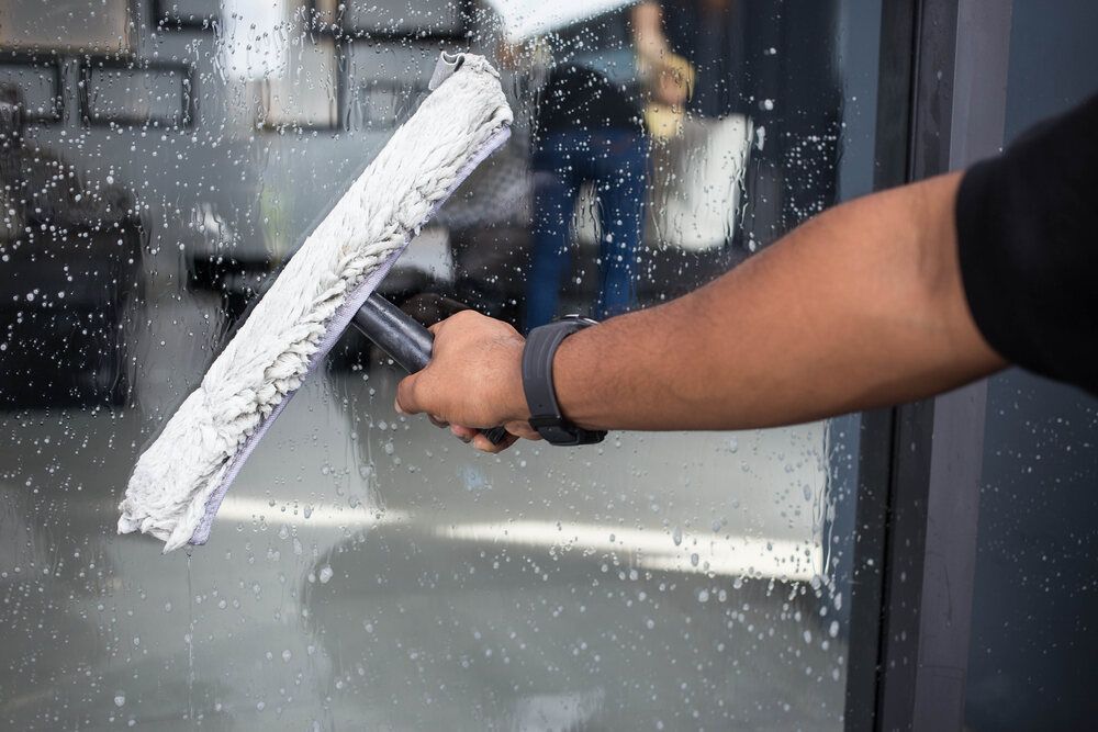 Person is Cleaning a Window With a Squeegee — Abstract Window Cleaning in Hopkins Creek, NSW