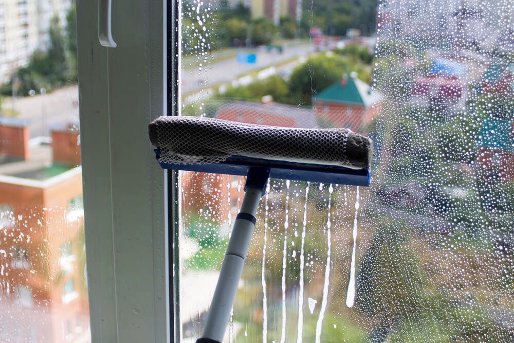 Person is Cleaning a Window With a Squeegee — Abstract Window Cleaning in Hopkins Creek, NSW