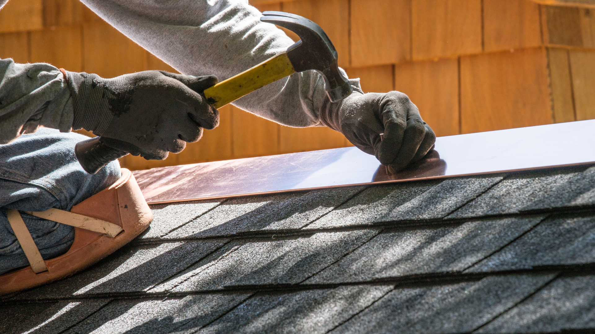 A man is working on a roof with a hammer.