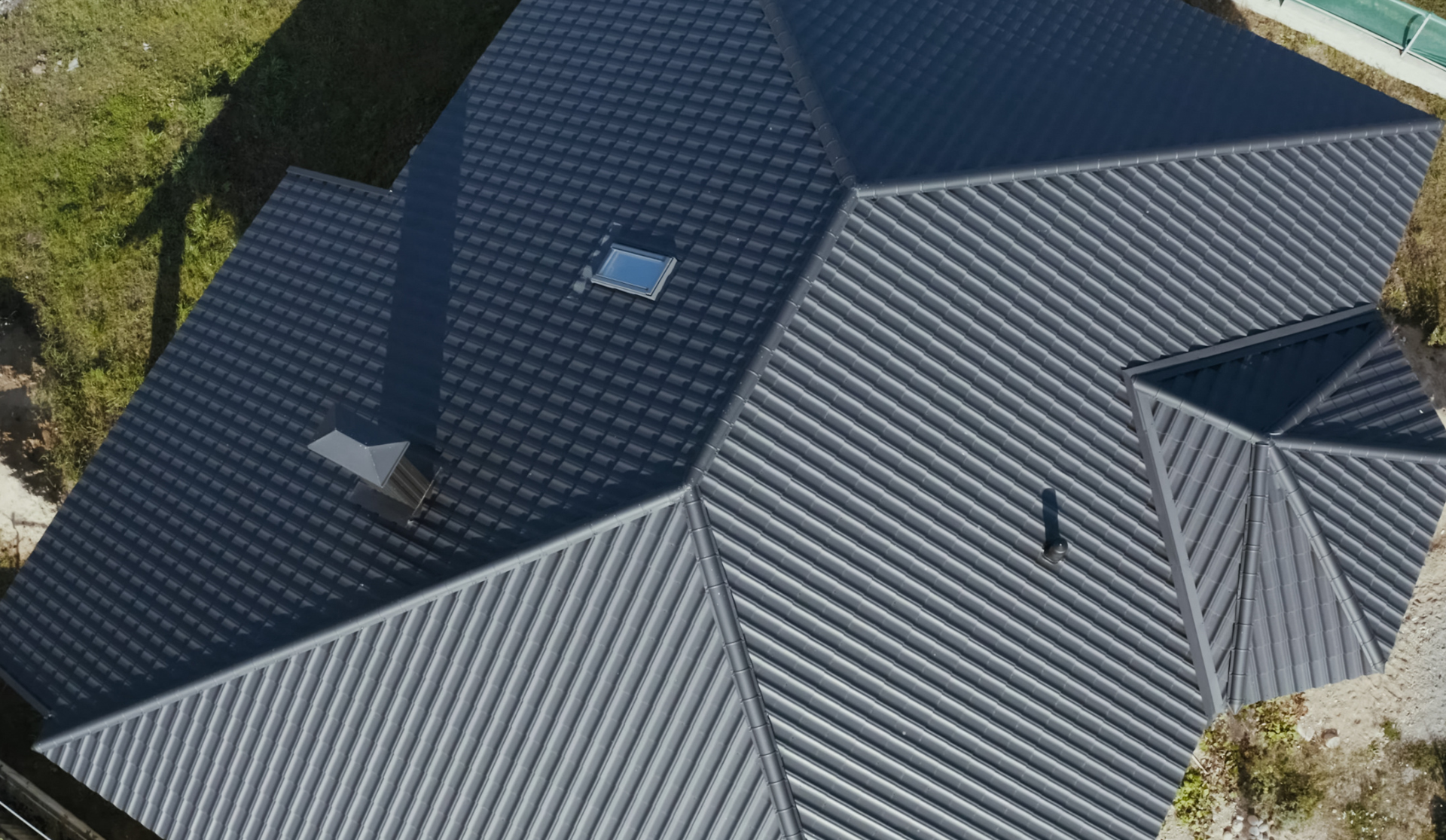An aerial view of a house with a black roof and a skylight.
