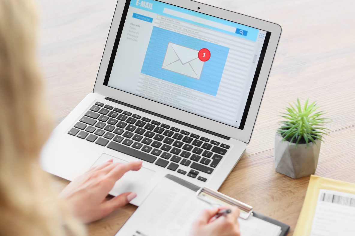 laptop with email notification and a person with a notepad