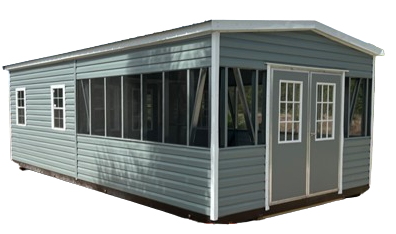 A white shed with black doors and shutters is sitting on top of a lush green field.