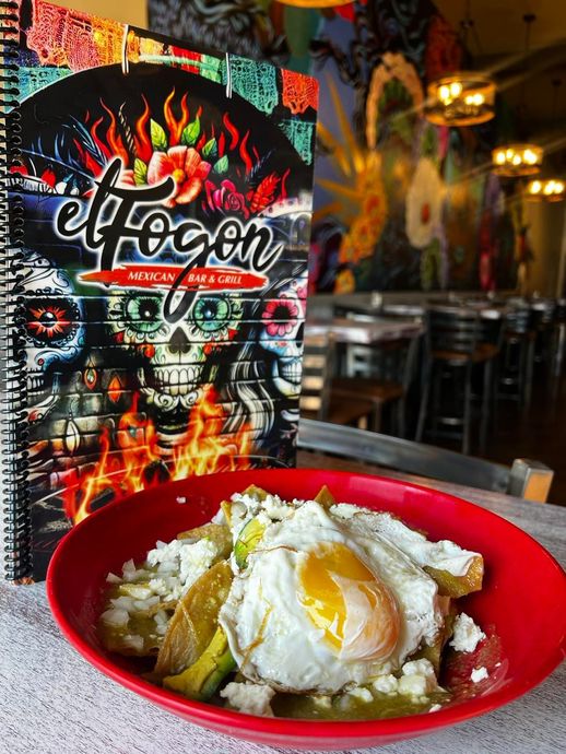 Chilaquiles with egg in a red bowl next to a menu from El Fogon Mexican Grill.