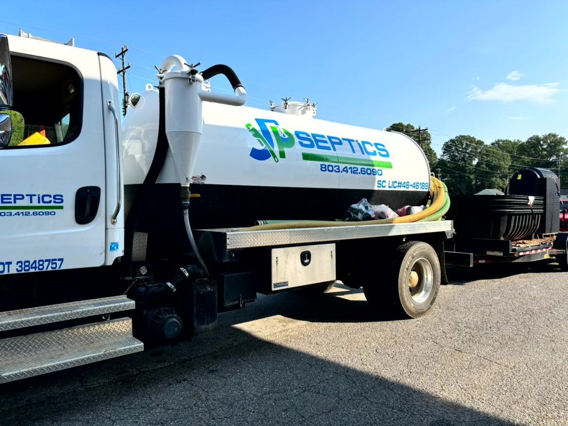 Septic tank truck with logo parked outdoors. White tank with blue and green lettering, yellow hose.
