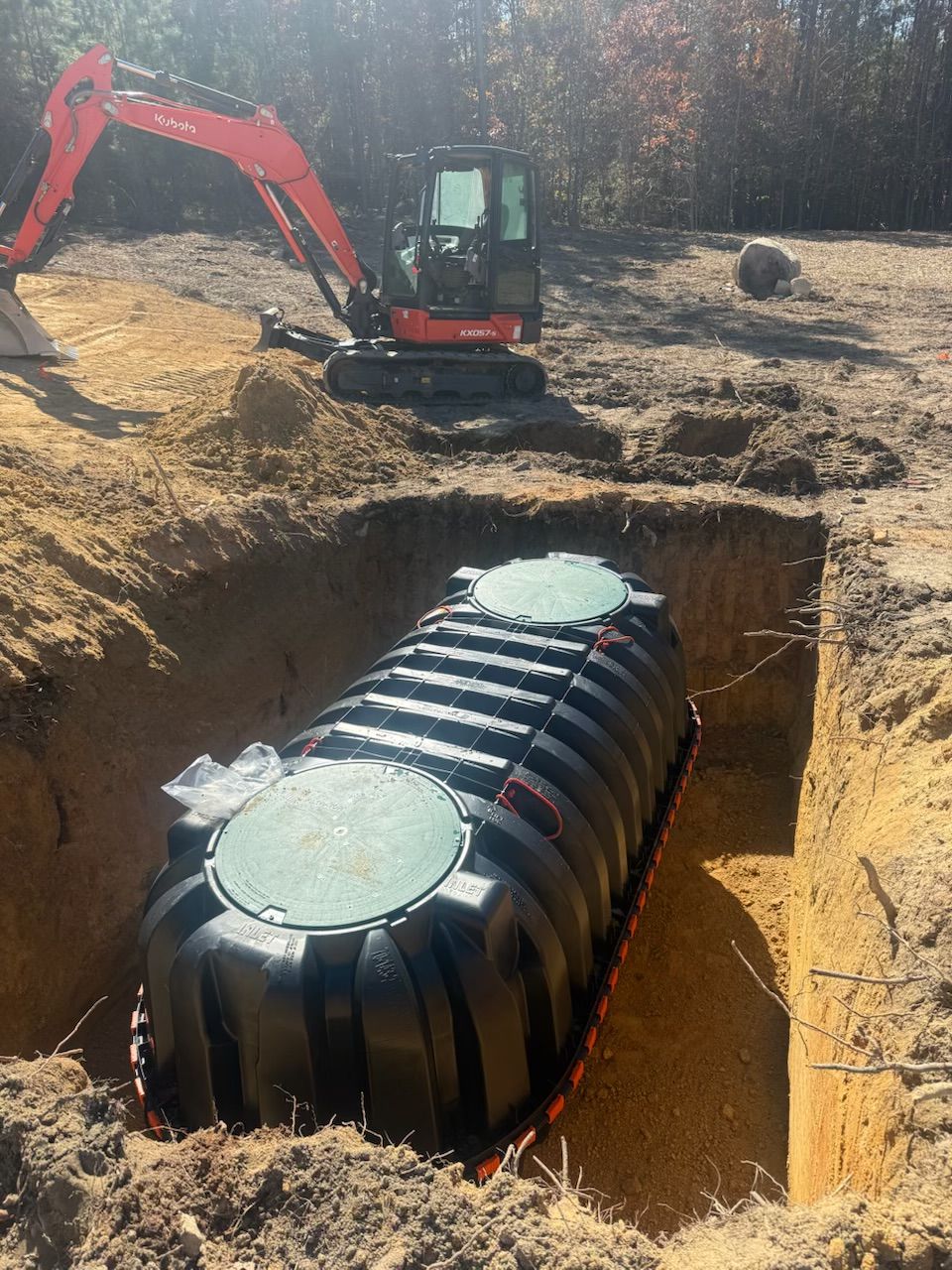 Excavator and septic tank in a hole on a construction site.
