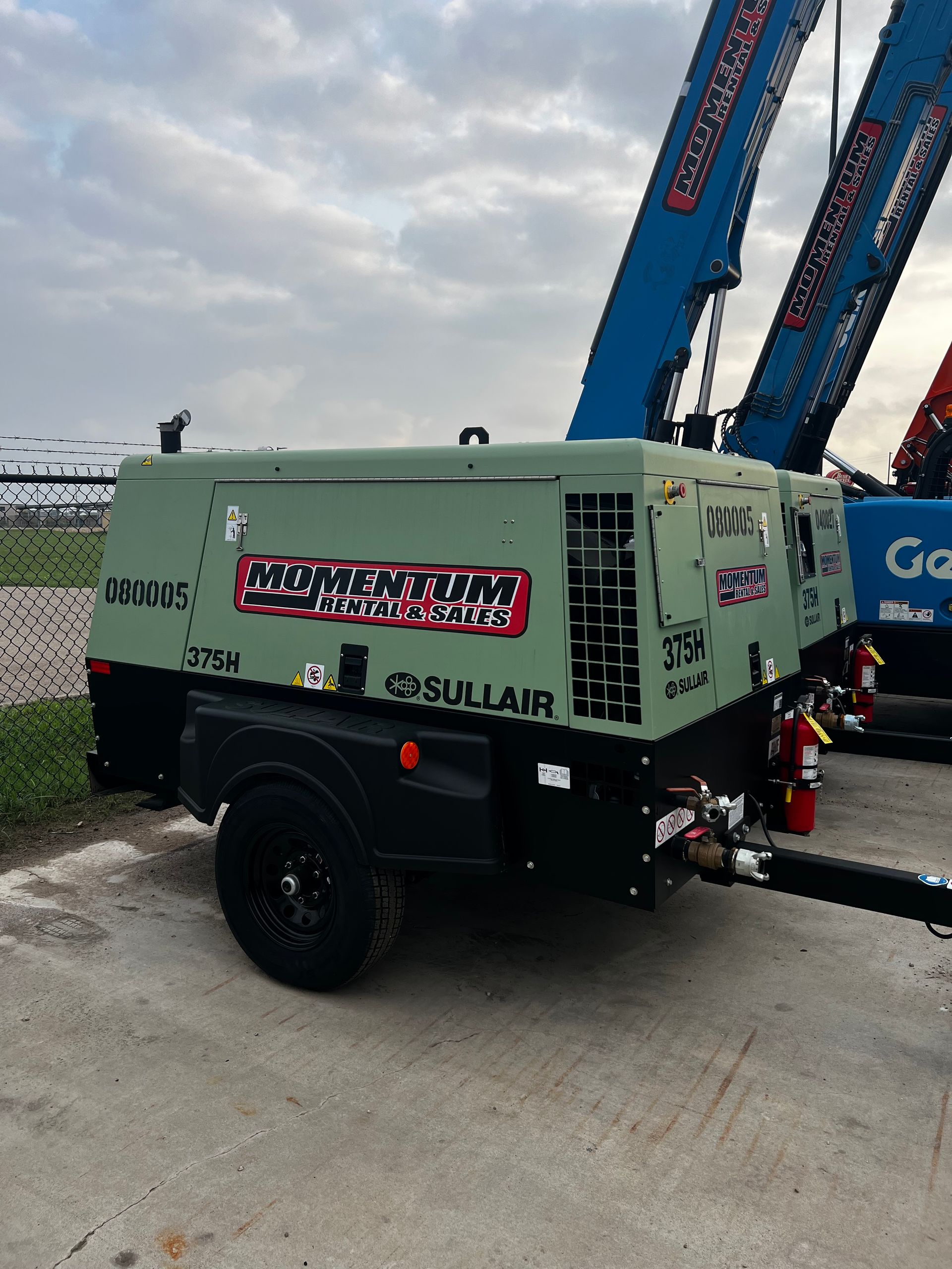 A green and black air compressor on a trailer on a white background.