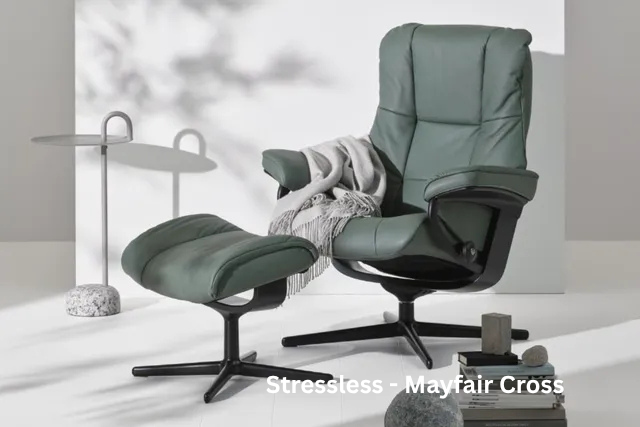 Green modern lounge chair with matching ottoman, gray blanket, and side table in a minimalist room