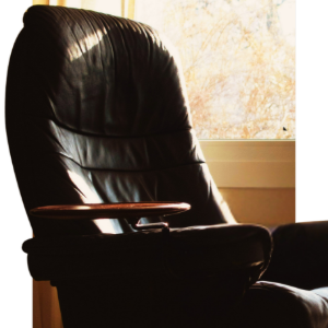 Black leather recliner by a sunlit window in a softly lit room