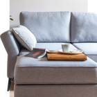 Gray sofa with a pillow, magazine, and tray holding a cup and saucer