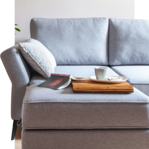 Gray sofa with a pillow, magazine, and tray holding a cup and saucer
