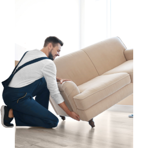 Man kneeling and lifting a beige sofa in a bright room