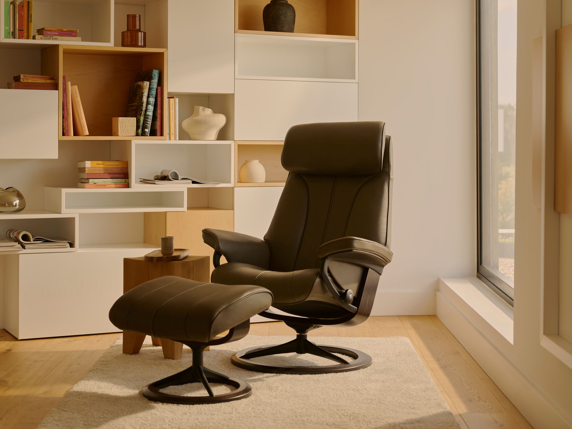 Comfortable office chairs and a person reclining in a tan lounge chair, shown in a modern furniture display.