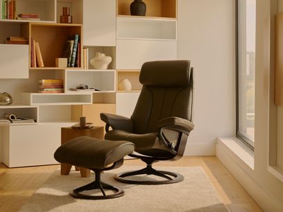 Modern living room with a black recliner, matching ottoman, and built-in shelves by a large window