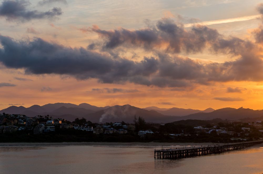 A Sunset Over a Body of Water With Mountains in Coffs Harbour — Currie Bros Engine Reconditioners in Coffs Harbour, NSW