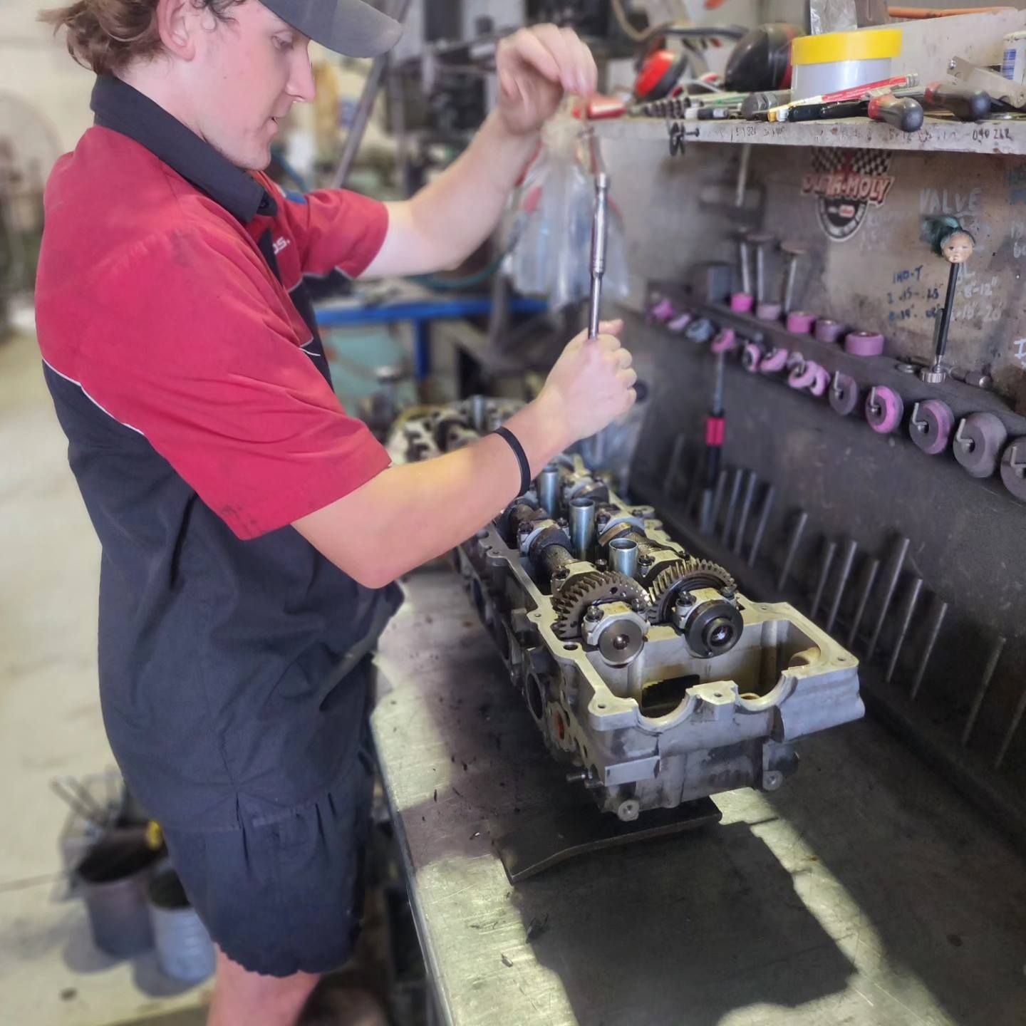 A Man in a Red Shirt is Working on a Machine — Currie Bros Engine Reconditioners in Hallidays Point, NSW 