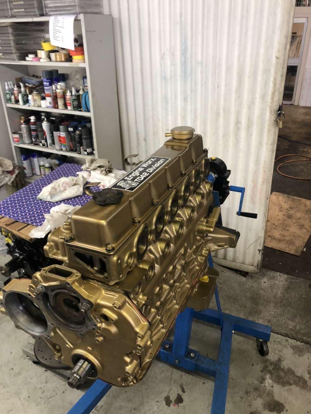 A Gold Engine is Sitting on a Blue Stand in a Garage — Currie Bros Engine Reconditioners in Wauchope, NSW