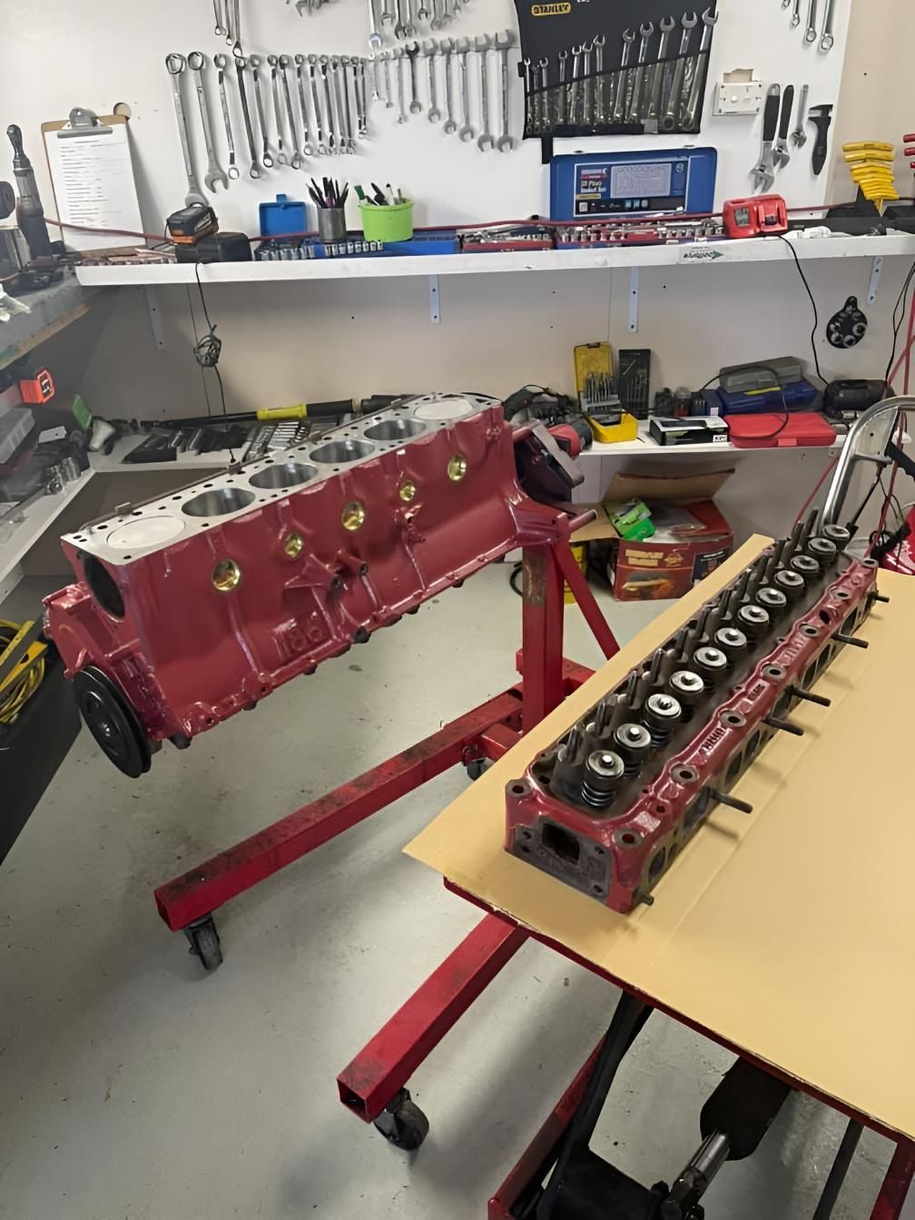 A Red Engine is Sitting on Top of a Wooden Table in a Garage — Currie Bros Engine Reconditioners in Port Macquarie, NSW