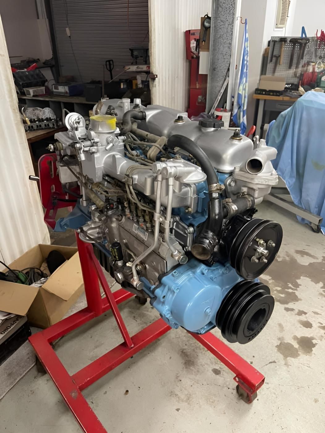 A Blue Engine is Sitting on a Red Stand in a Garage — Currie Bros Engine Reconditioners in Forster, NSW