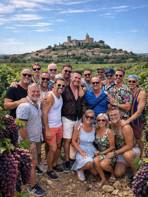 Group of people posing in a vineyard with a hilltop village and castle in the background.