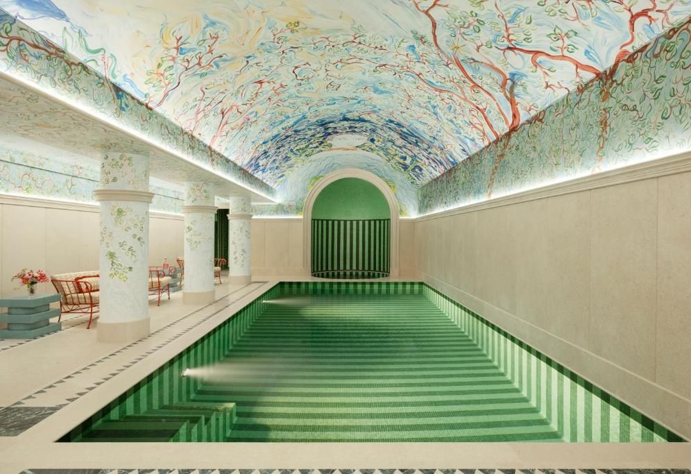 Indoor pool with green steps and a painted arched ceiling in a spa-like hall
