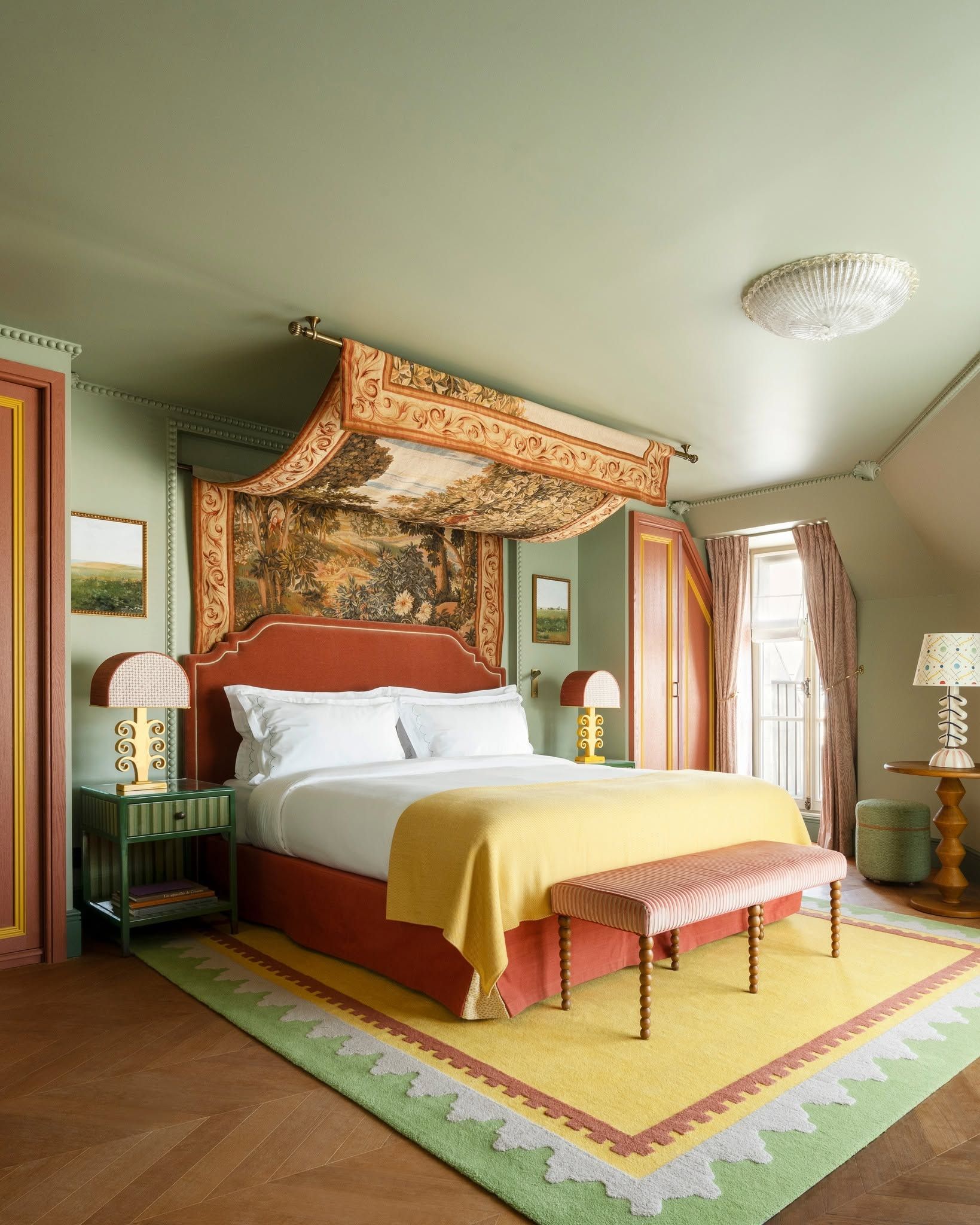 Stylish bedroom with a canopy bed, yellow throw, patterned rug, and soft green walls