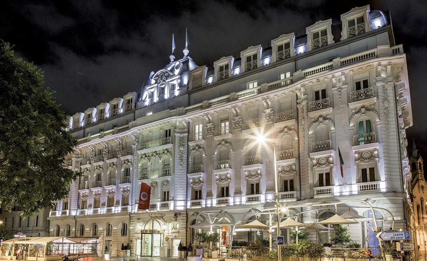 Illuminated historic building at night with ornate facade and streetlights.