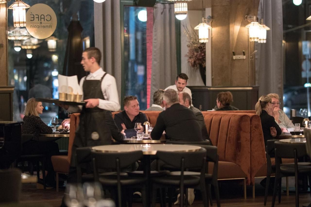 People dining in a warm, dimly lit restaurant with a waiter serving at a table.
