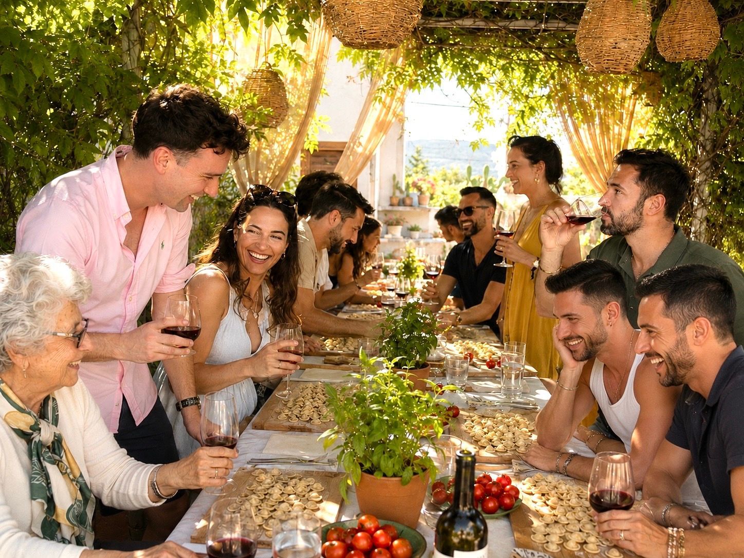People gathered around a long outdoor table under a leafy canopy, chatting and eating at a garden meal.