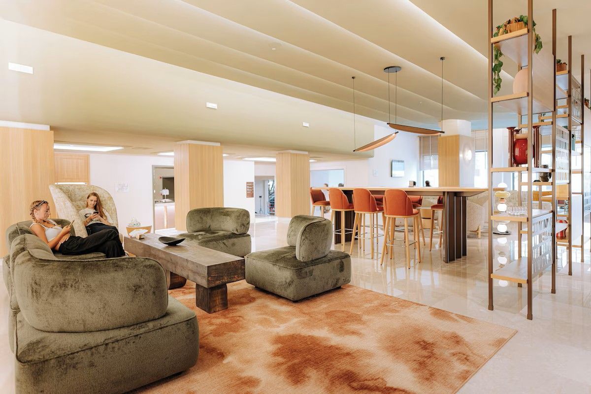 Modern living room with plush chairs, shag rug, and open kitchen with bar stools