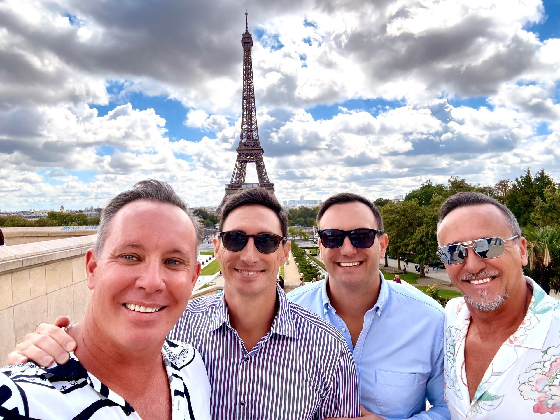 Four guests posing in front of the Eiffel Tower, gay tour of Paris