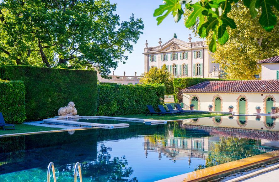 Formal garden with a reflecting pool, fountain, and a grand white mansion in the background