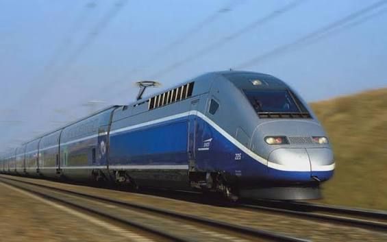 Blue passenger train speeding along tracks through a rural landscape