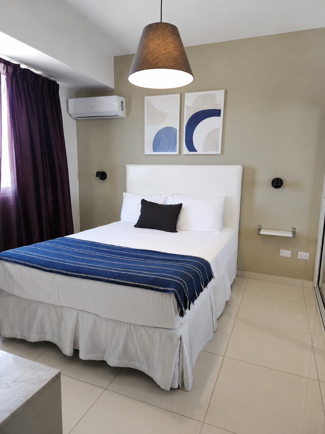 Dormitorio moderno con cama, paredes grises, cortinas azules y arte abstracto en la pared.
