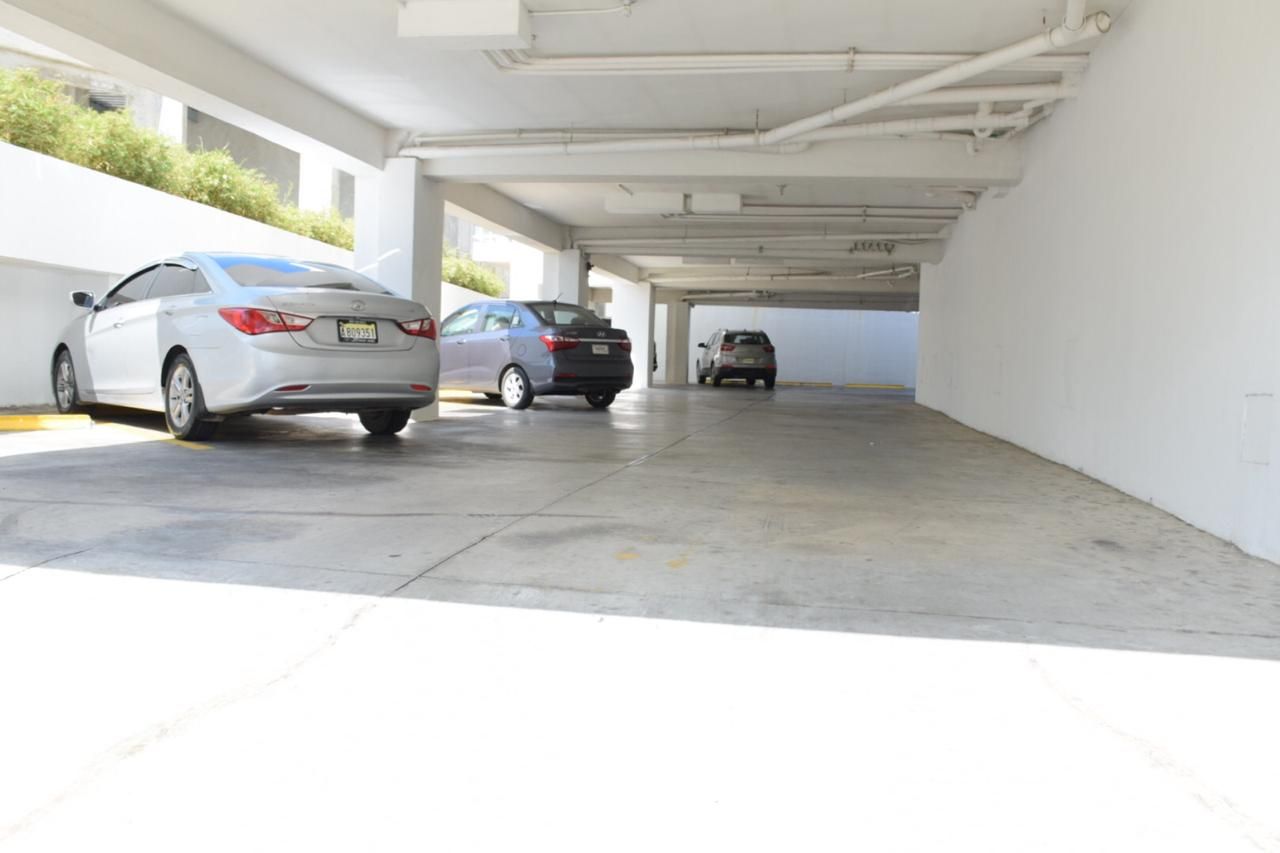 Garaje cubierto con varios coches aparcados a plena luz del día.
