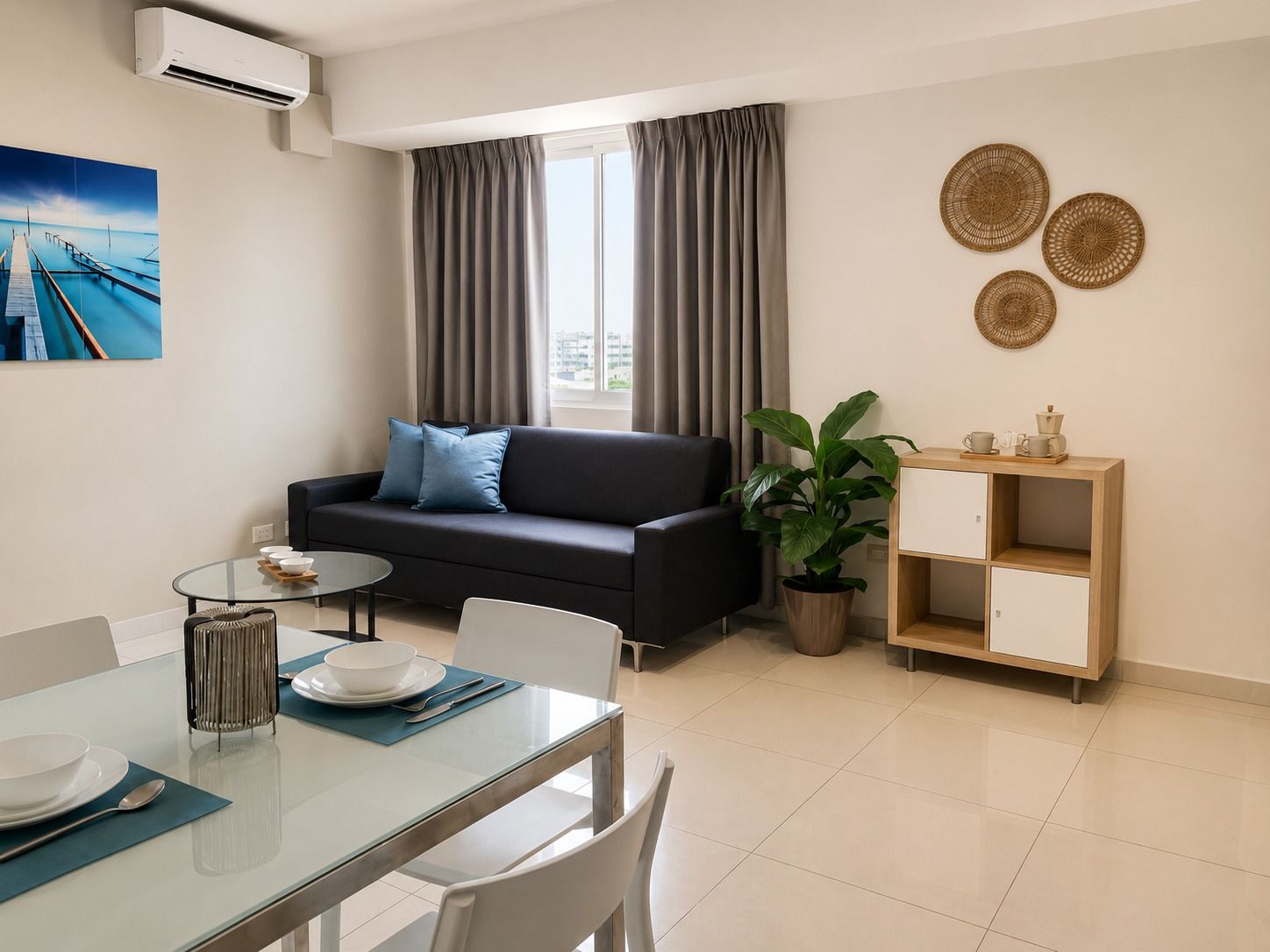 Habitación minimalista con cama, televisor sobre mueble blanco y gran ventanal con vistas a la ciudad.