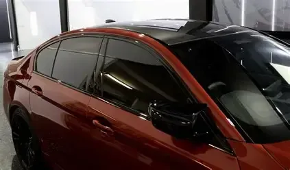 A person wearing gloves is working on a car's brake disc and caliper.
