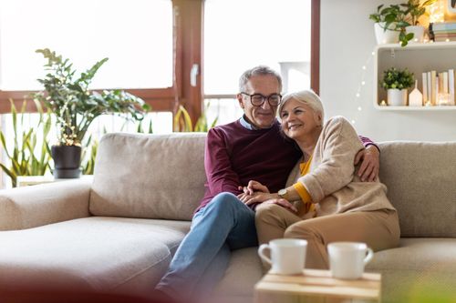 Smiling couple sitting together on a beige sofa in a bright living room